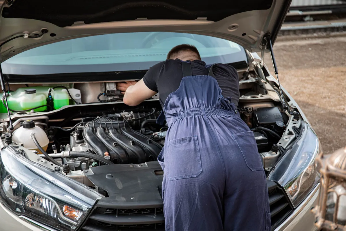 Kaputu açık aracın motoruna eğilmiş tulumlu bir usta