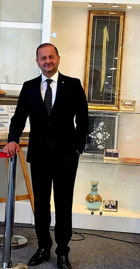 ELSADER heyetinden bir kişi cam vitrinli bir salonda ayakta