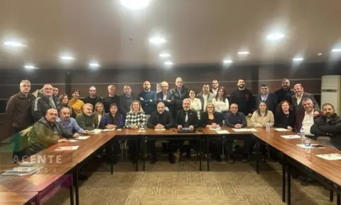 TÜSAF üyeleri toplantı salonunda U şeklinde masalarda toplu poz veriyor